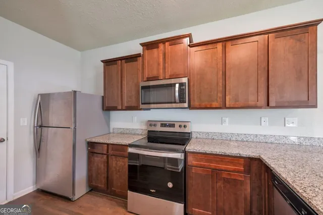 a kitchen with granite countertop a refrigerator stove and microwave