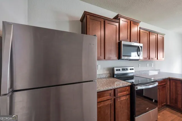 a kitchen with stainless steel appliances granite countertop a refrigerator a microwave a sink and cabinets