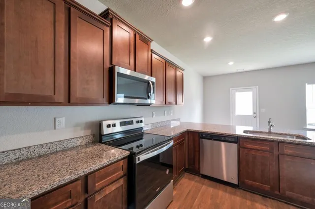 a kitchen with stainless steel appliances granite countertop a sink stove and microwave