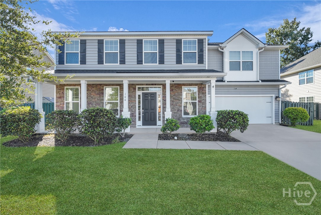 Two-story traditional home with front porch, white siding, black shutters, attached garage, manicured lawn, and landscaped shrubs under a clear blue sky.