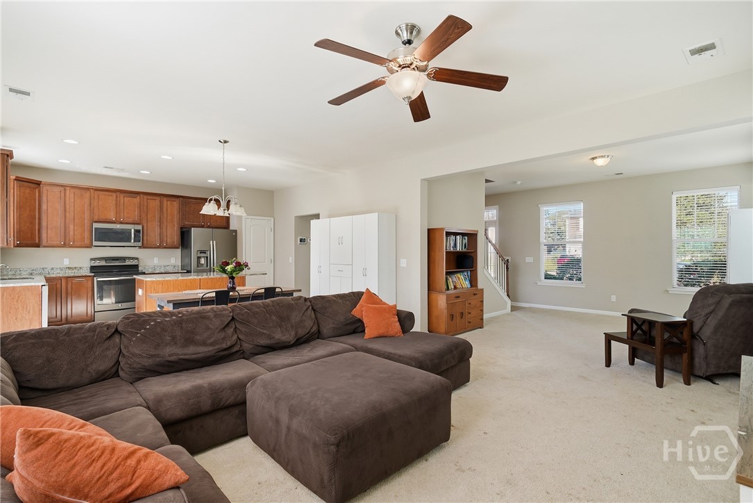 100 Smoke Rise Road Richmond Hill, GA 31324 - Photo 19 of 50 Open concept main floor with carpeted living area, ceiling fan, neutral wall color, and view into the kitchen.