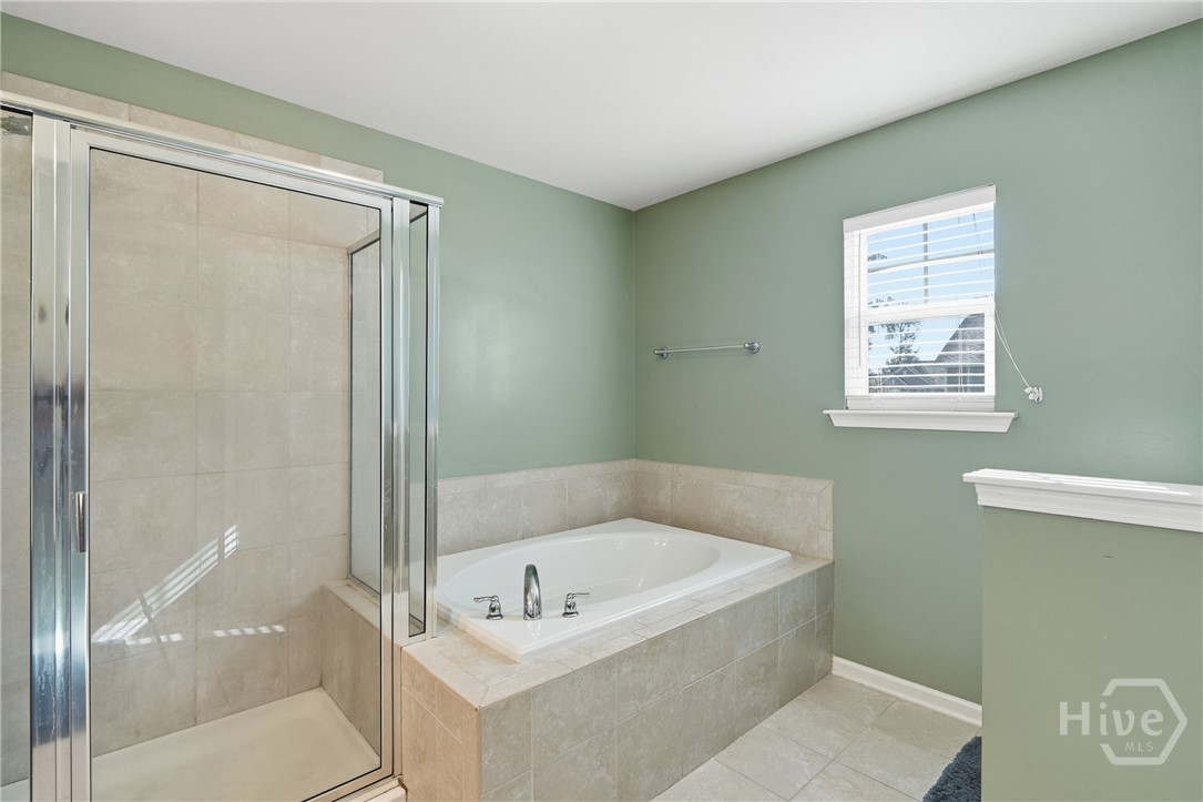 100 Smoke Rise Road Richmond Hill, GA 31324 - Photo 27 of 50 Bathroom with tiled walk-in shower and separate soaking tub with tile surround, green painted walls, and a window.