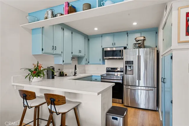 a kitchen with stainless steel appliances a refrigerator a stove a sink cabinets and a dining table