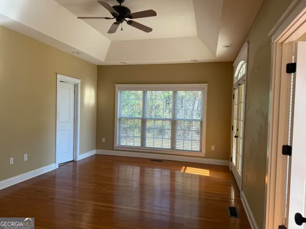 a view of empty room with wooden floor and fan