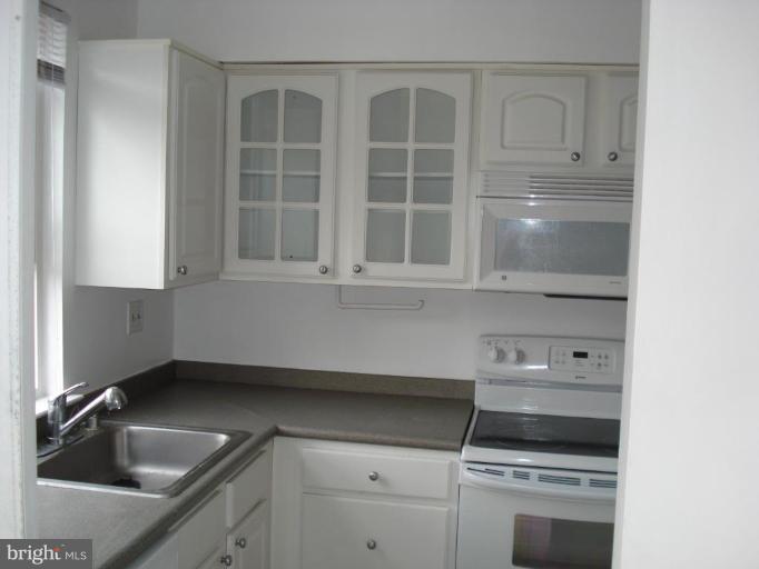 46 Ritters Ridge Court, Unit 46 Owings Mills, MD 21117 - Photo 3 of 8 a kitchen with white cabinets and a stove