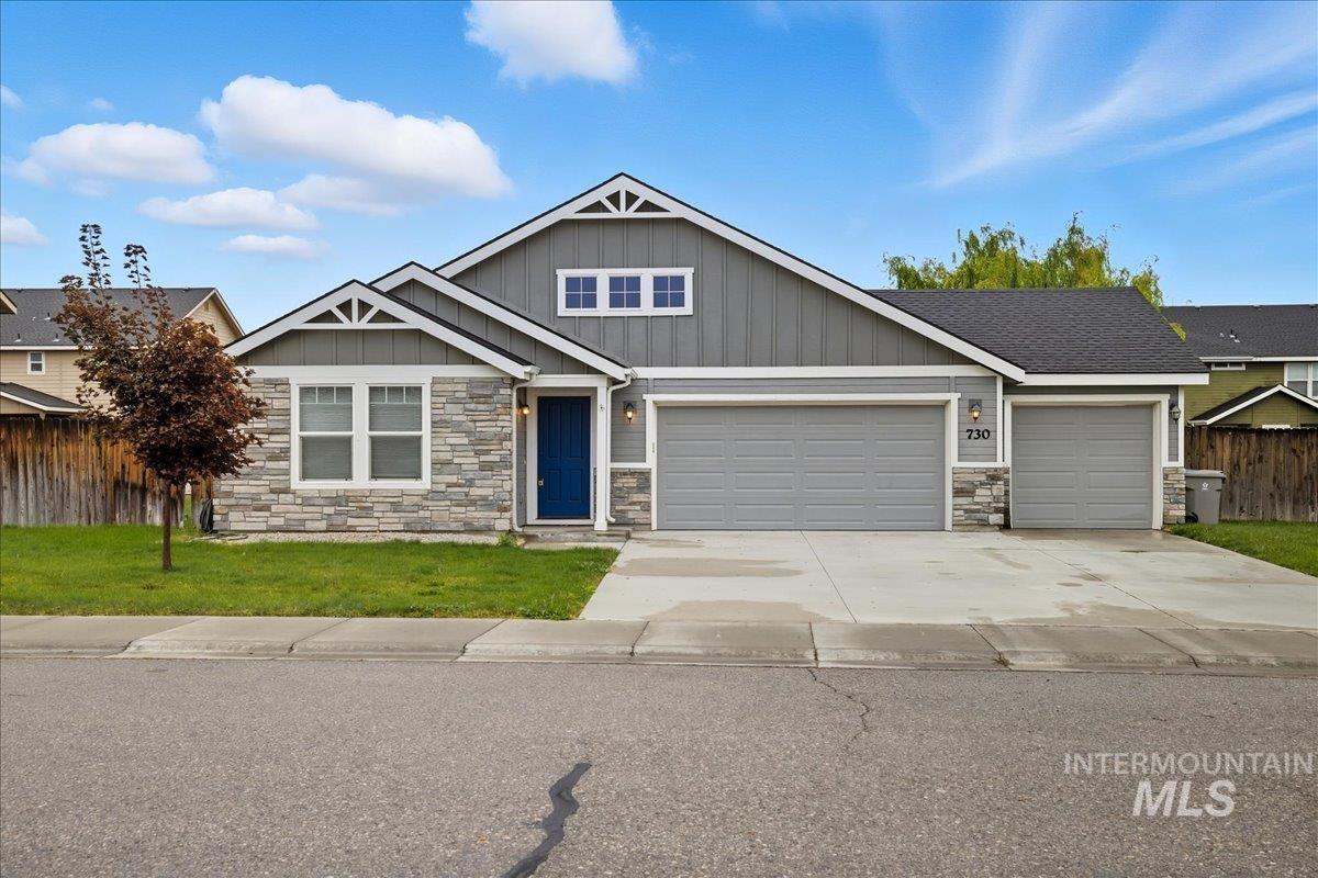 Craftsman-style house featuring stone siding, driveway, an attached garage, and board and batten siding