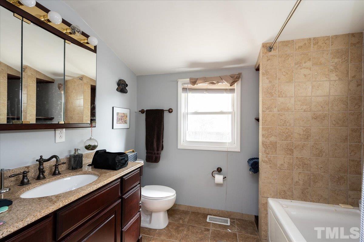 302 Georgetown Road Raleigh, NC 27608 - Photo 14 of 19 a bathroom with a granite countertop sink toilet a mirror a vanity and shower