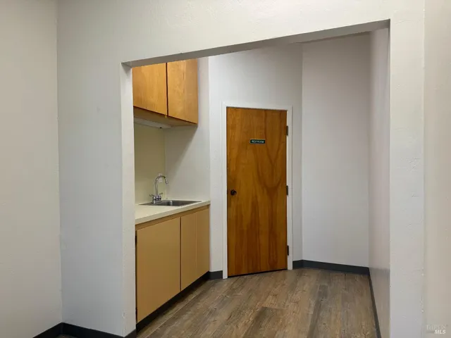 a view of kitchen with wooden floor and cabinets