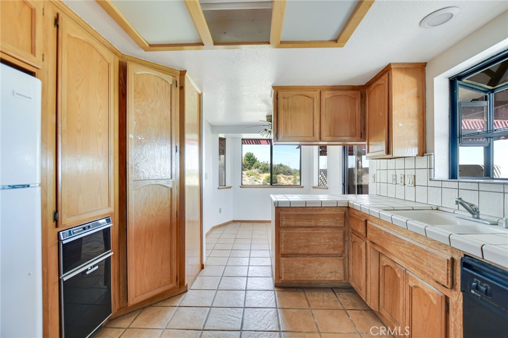 2929 Snow Line Drive Pinon Hills, CA 92372 - Photo 19 of 67 a kitchen with stainless steel appliances granite countertop a refrigerator and a sink