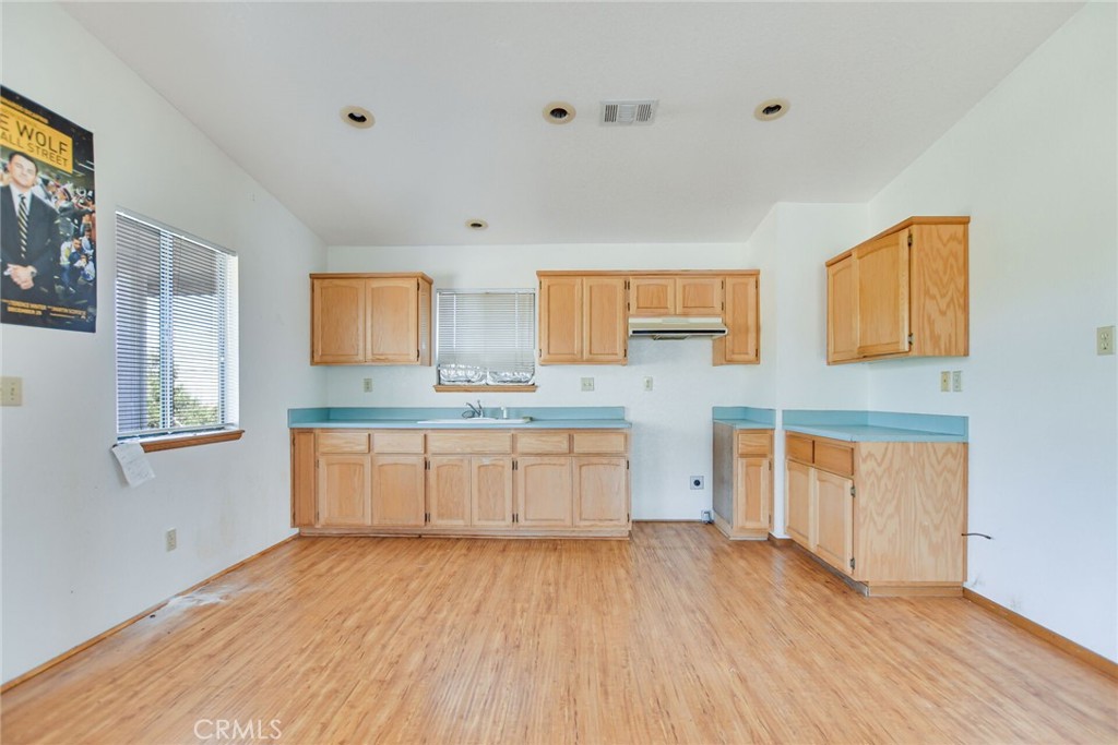 2929 Snow Line Drive Pinon Hills, CA 92372 - Photo 46 of 67 a large white kitchen with granite countertop a stove top oven a sink and dishwasher with wooden floor