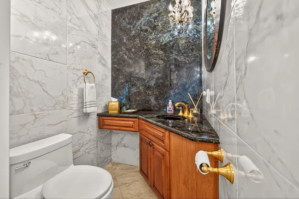 a bathroom with a granite countertop sink and a toilet