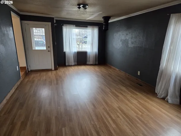 an empty room with wooden floor and windows