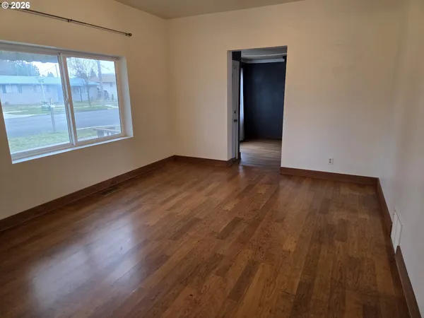 an empty room with wooden floor and windows