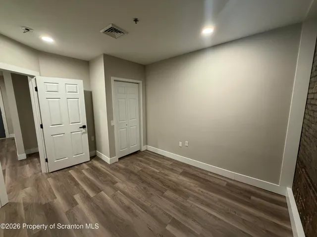 an empty room with wooden floor and a refrigerator