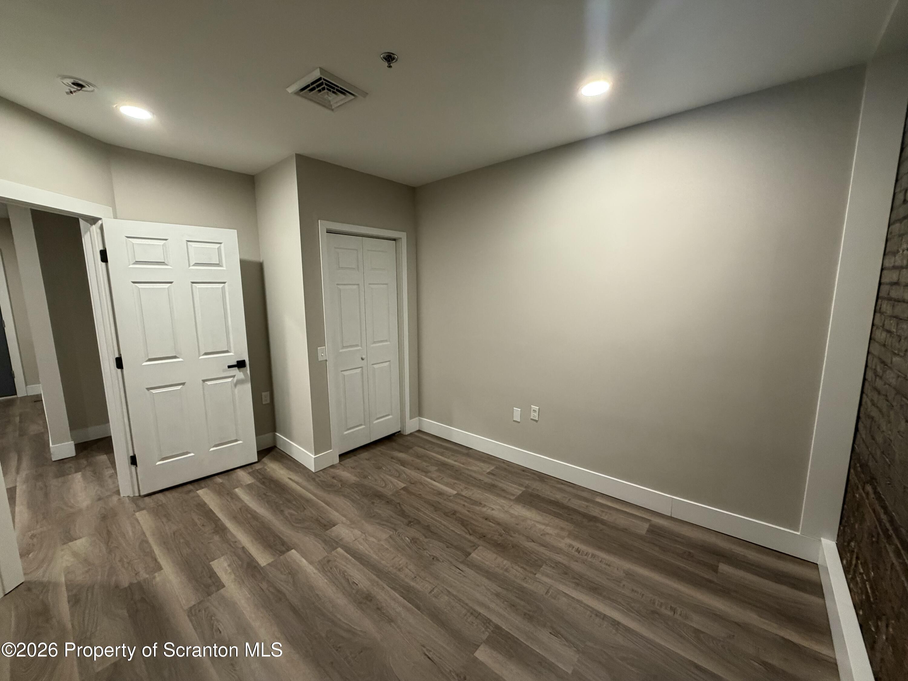 205 North Washington Avenue, Unit 7 Scranton, PA 18503 - Photo 5 of 7 an empty room with wooden floor and a refrigerator