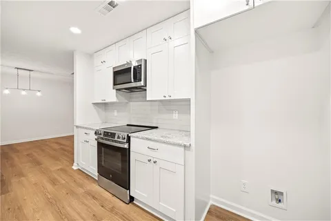 a kitchen with stainless steel appliances white cabinets and a stove top oven