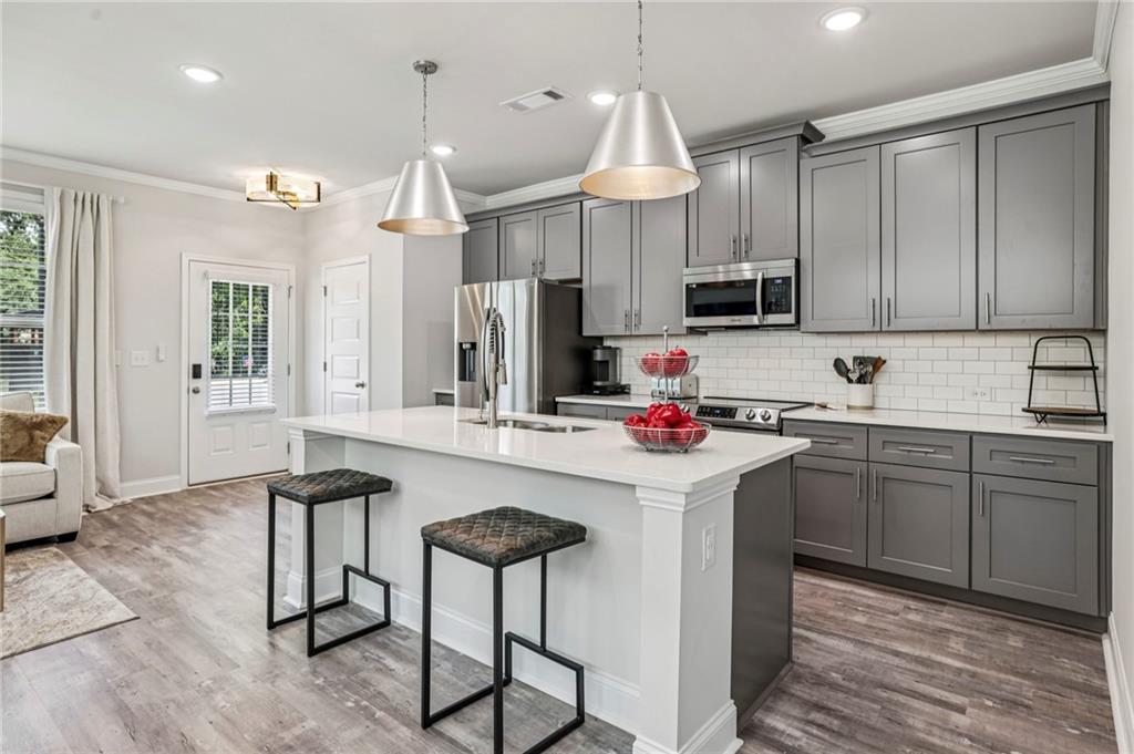 5064 Insperon Lane, Unit 34 Peachtree Corners, GA 30092 - Photo 7 of 48 a kitchen with kitchen island granite countertop a sink cabinets and refrigerator