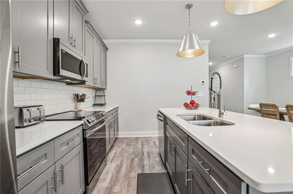 5064 Insperon Lane, Unit 34 Peachtree Corners, GA 30092 - Photo 9 of 48 a kitchen with stainless steel appliances granite countertop a sink a stove and a wooden floors