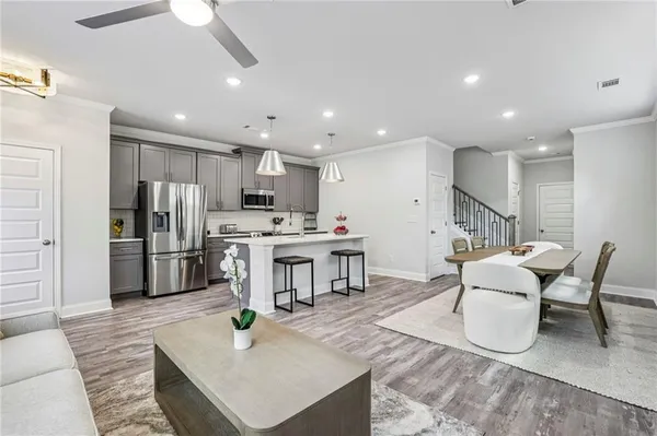 a kitchen with stainless steel appliances kitchen island granite countertop a refrigerator a stove a sink a dining table and chairs with wooden floor