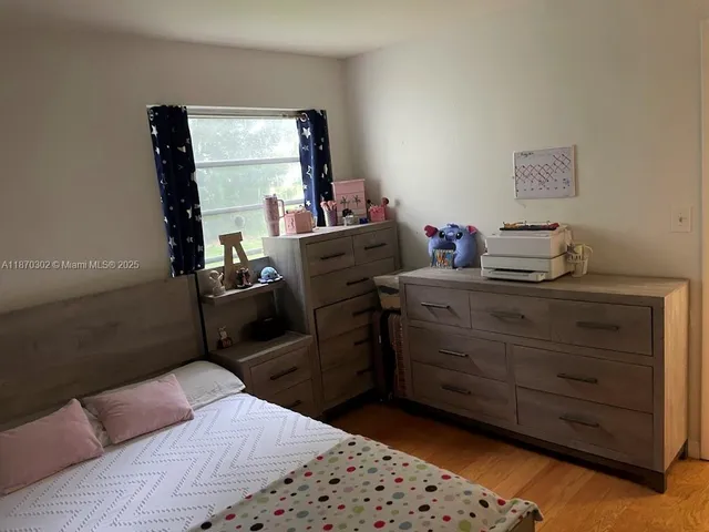 a bedroom with a bed and a flat tv screen on the dresser