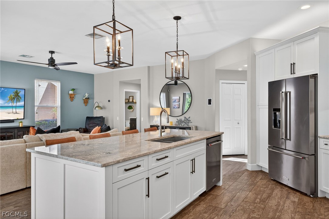 22866 Forest Ridge Drive Estero, FL 33928 - Photo 5 of 38 a kitchen with stainless steel appliances granite countertop a sink a refrigerator and a wooden floors
