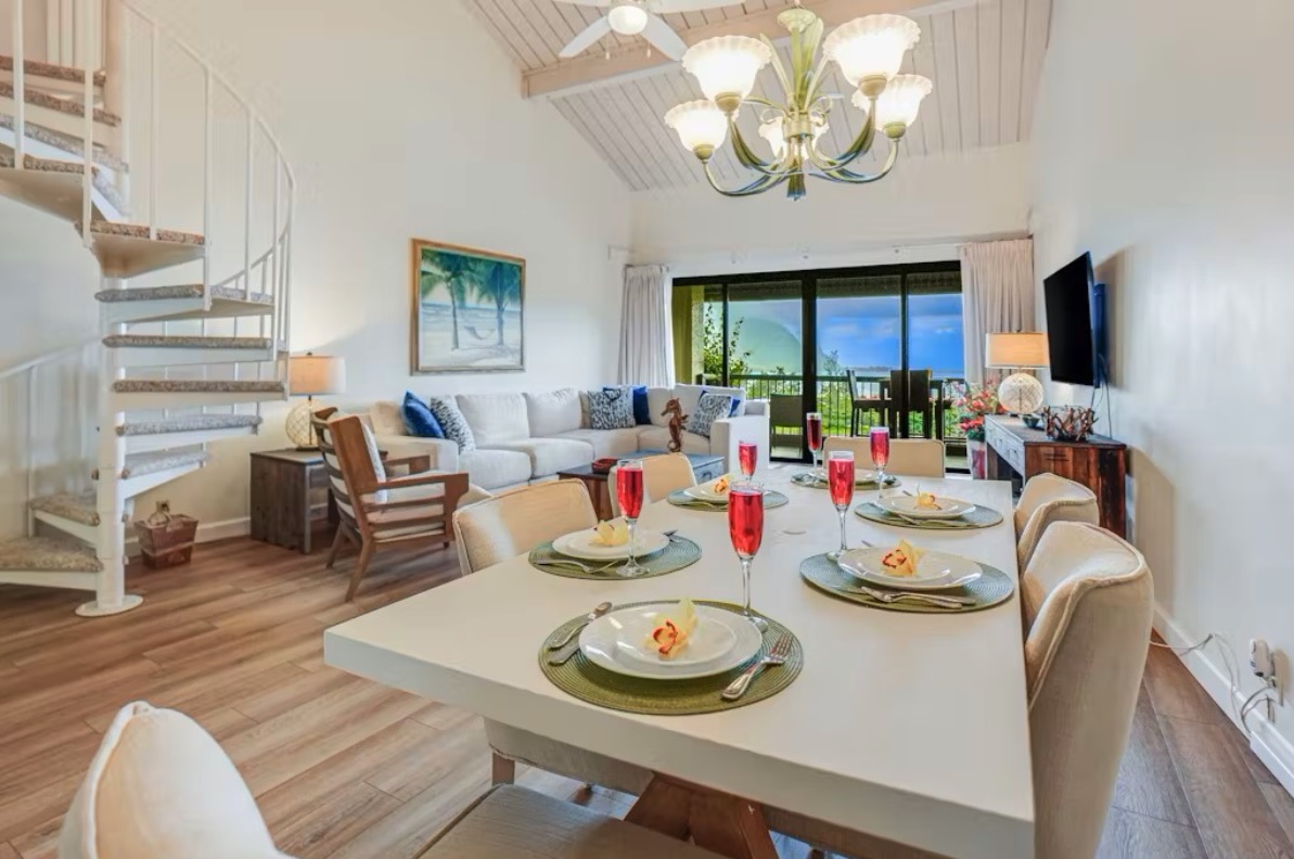 5380 Honoiki Road, Unit J33 Princeville, HI 96722 - Photo 11 of 30 a view of a dining room with furniture a chandelier windows and wooden floor