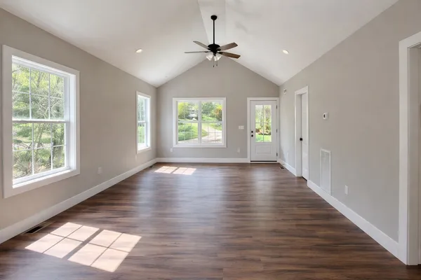 a view of an empty room with wooden floor and a window