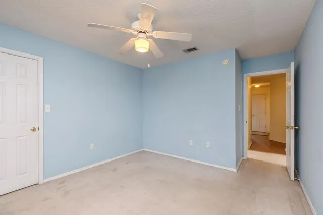 an empty room with a chandelier fan and a bathroom