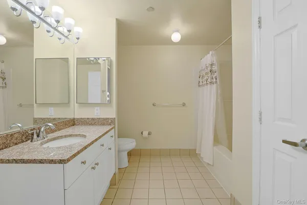 a bathroom with a granite countertop sink a toilet and a mirror