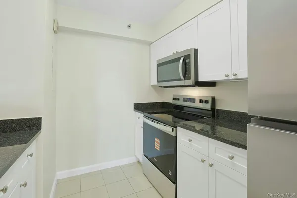 a kitchen with granite countertop white cabinets and stainless steel appliances
