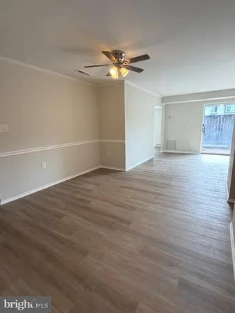 a view of a livingroom with wooden floor a ceiling fan and windows