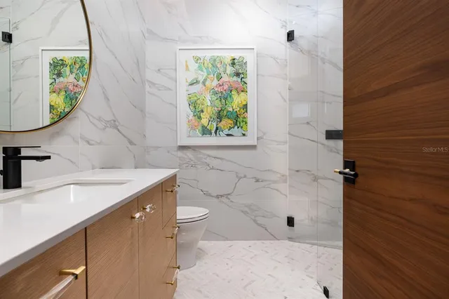 a bathroom with a granite countertop sink a toilet and a shower