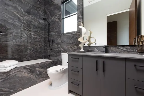 a bathroom with a granite countertop toilet sink and mirror