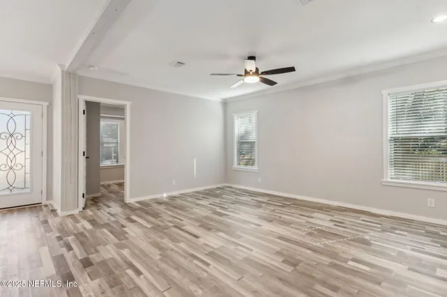 a view of empty room with wooden floor and fan