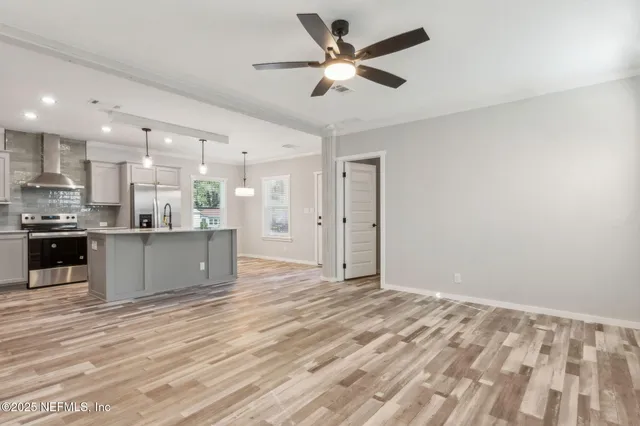 a view of kitchen with kitchen island stainless steel appliances wooden floor cabinets and a ceiling fan