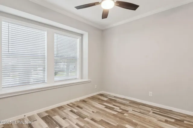 an empty room with a window and a ceiling fan