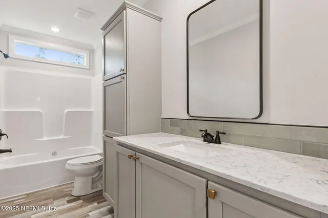 a bathroom with a granite countertop sink a toilet and a large mirror