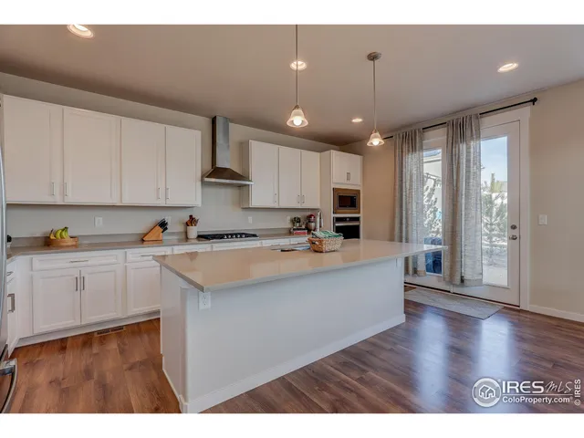 a large white kitchen with lots of counter space a sink appliances and cabinets