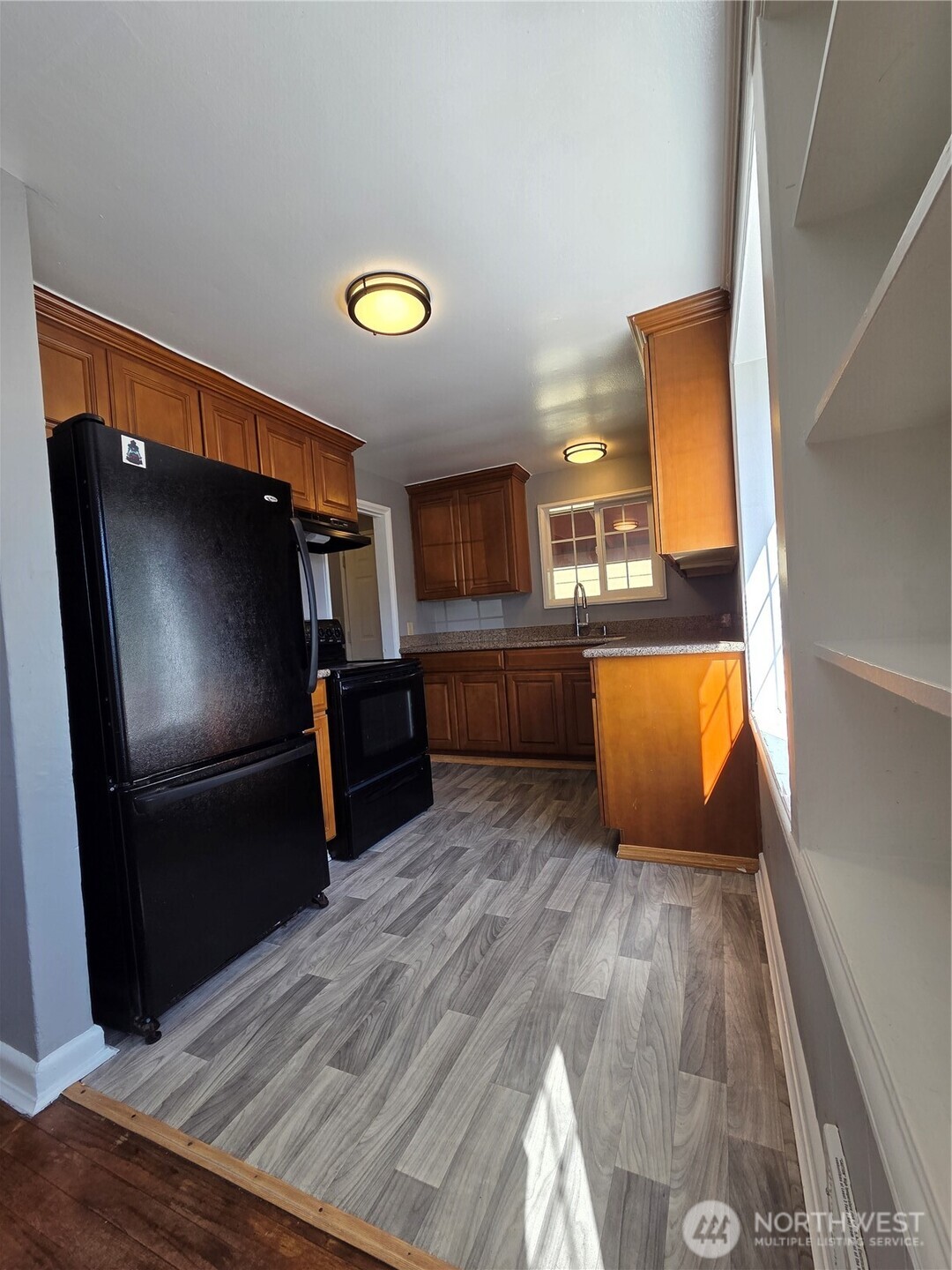 10603 12th Avenue Southwest Seattle, WA 98146 - Photo 8 of 14 a kitchen with wooden floors and stainless steel appliances