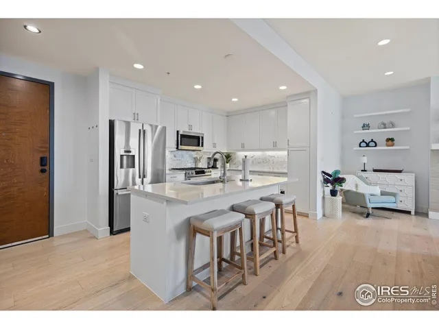 a kitchen with stainless steel appliances kitchen island granite countertop a refrigerator and a sink