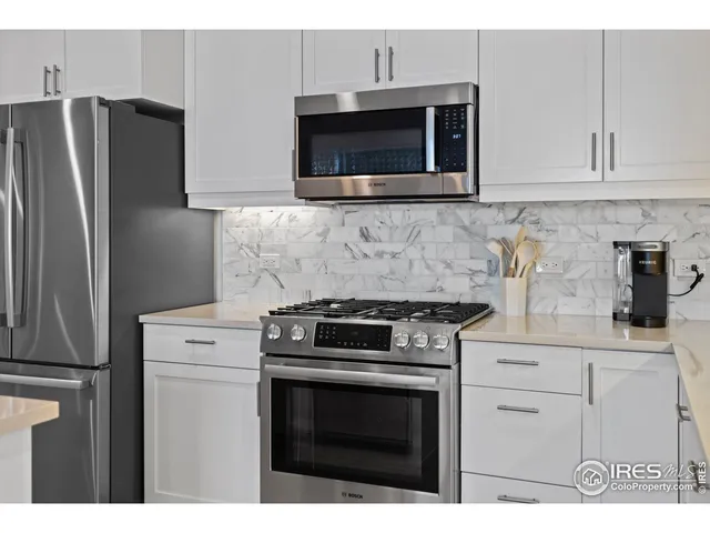 a kitchen with stainless steel appliances granite countertop white cabinets a microwave a sink and a refrigerator