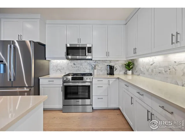 a kitchen with stainless steel appliances granite countertop a refrigerator sink and white cabinets