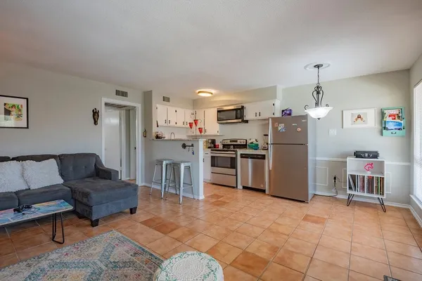 a living room with a couch and a dining table with kitchen appliances