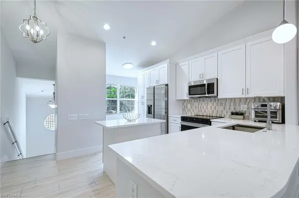 a kitchen with stainless steel appliances a white refrigerator a stove a microwave and cabinets