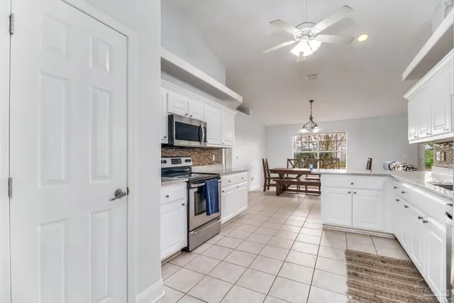 a kitchen with stainless steel appliances kitchen island granite countertop a table chairs and a refrigerator