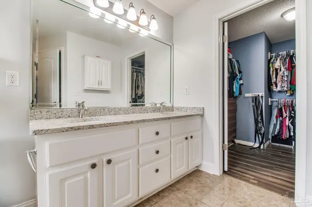 a bathroom with a granite countertop double vanity sink a bathtub and mirror