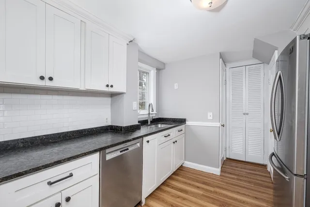 a kitchen with granite countertop white cabinets and stainless steel appliances