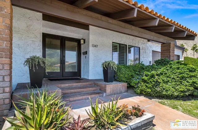 a view of a house with a yard and potted plants