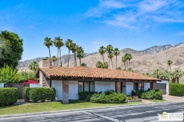 a front view of a house with a yard and potted plants