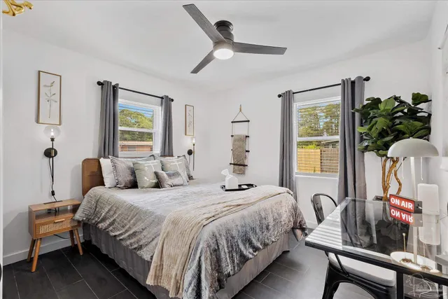a bedroom with a bed a potted plant on dresser and a window